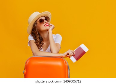 concept of travel. happy woman girl with suitcase and passport on  yellow colored background
