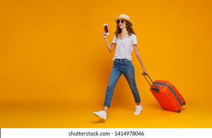 concept of travel. happy woman girl with suitcase and passport on  yellow colored background