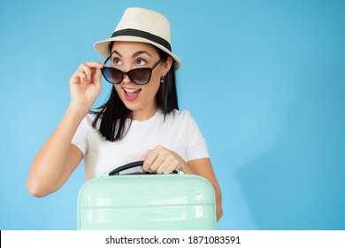 Concept Of Travel. Happy Woman Wearing Straw Hat And Sunglasses With Suitcase And Passport On Blue Colored Background