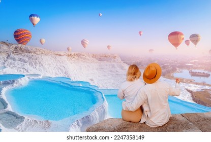 Concept Travel tourist background Pamukkale Turkey. Lover couple watching Hot air balloon flying Travertine pool and terraces.