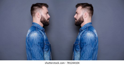 Concept of the twins. Two twin brothers in jeans shirts look at each other against a gray background.
