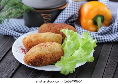 Concept of Ukrainian cuisine. Kiev cutlets with lettuce and pepper. Chicken cutlets with filling on a dark wooden background. Background image, copy space