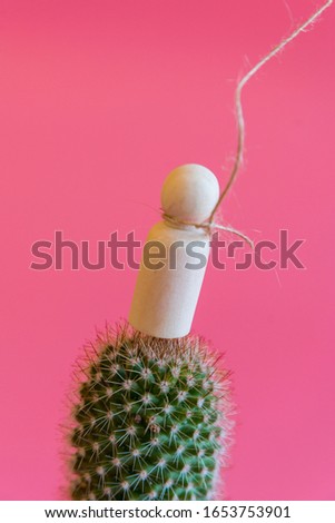 The concept of unbearable pain. Pain leads to suicide.Figurine of a man on needles with a noose around his neck on a pink background. vertical photo