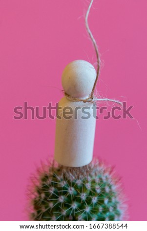 The concept of unbearable pain. Pain leads to suicide.Figurine of a man on needles with a noose around his neck on a pink background. copy space. vertical photo
