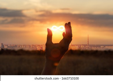 Concept of unlimited Internet. Hand shows the sign of infinity in the sun.