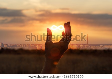 Concept of unlimited Internet. Hand shows the sign of infinity in the sun.