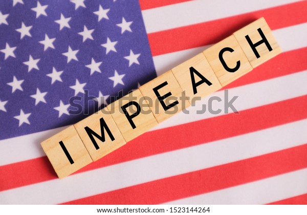 Concept of US politics, Impeachment\
showing with US flag with Impeach in wooden\
letters.