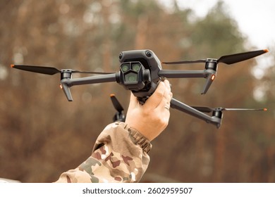 Concept of using drones in modern warfare. Close-up of a drone in hands of a soldier. Military use of drones