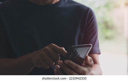 The Concept Of Using The Phone Is Essential In Everyday Life. Close Up Of A Man Using A Smartphone In Public Areas, During Leisure Time.