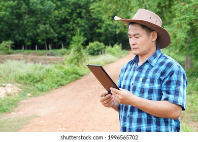 Concept : using wireless internet . Handsome Asian man wears hat and hold smart tablet to check wifi and internet signal in far away rural area in Thailand. - Powered by Shutterstock