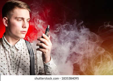 The concept of vaping in red. A young man with an electronic cigarette in his hands against the background of smoke. Space for text. VAPE shop. Smoking electronic cigarettes.  