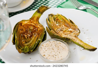 Concept of vegetarian food. Chopped fried artichokes sprinkled with koshering salt served with white sauce..