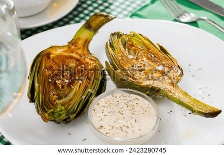 Concept of vegetarian food. Chopped fried artichokes sprinkled with koshering salt served with white sauce..