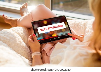 Concept of video marketing, woman looking at ad banner while watching videos online on tablet