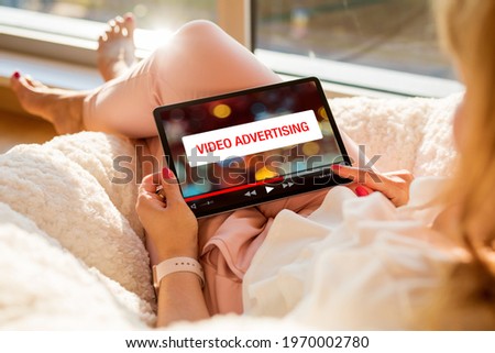 Concept of video marketing, woman looking at ad banner while watching videos online on tablet