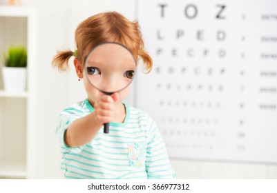 concept vision testing. child girl with a magnifying glass at the doctor ophthalmologist