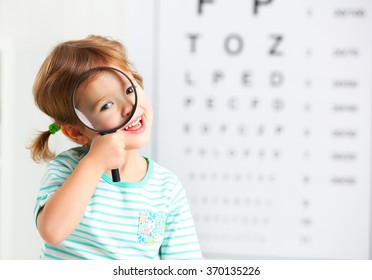 concept vision testing. child girl with a magnifying glass at the doctor ophthalmologist
