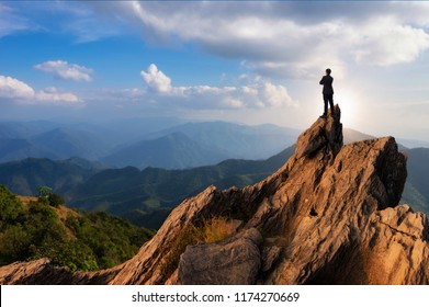 Concept vision, Young businessman wearing comfortable casual suit jacket standing chest hug on top of peak mountain and looking forwards, success, competition and leader concept.