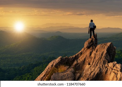 Concept vision, Young businessman wearing comfortable casual suit jacket standing holding business bag on top of peak mountain and looking forwards, success, competition and leader concept. - Shutterstock ID 1184707660