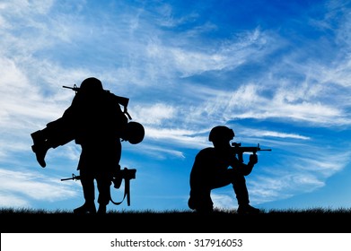 Concept Of War. Silhouette Of A Soldier Carries A Wounded Soldier On A Background Of Sky