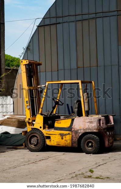 Concept\
of warehouse. the forklift on the street near a metal wall. yellow\
forklift. loader near the warehouse. old\
loader