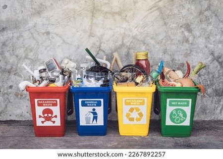 The concept of waste classification for recycling. Collection of waste bins full of different types of garbage in separation according to the color of the bin with old wall background.