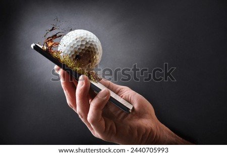 Concept of watching golf online with hand holding a mobile phone with ball and dark gray isolated background.