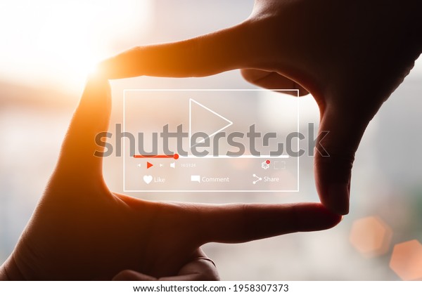 Concept of watching live video online,\
hands making framing view on blurred sunset\
background.