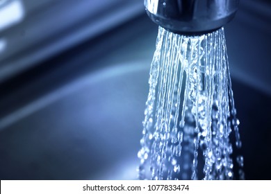 Concept Water Saving At Home, Reducing Use. Water Supply Problems. Water Tap With Flowing Water With Spray. Selective Focus