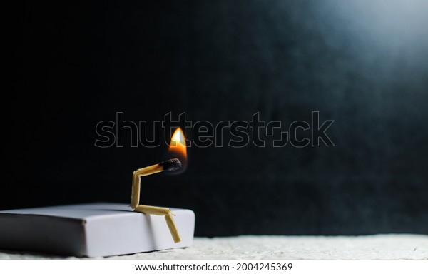 Concept of weakness, sadness,\
and loneliness. Image of a man-made matchstick. Burning matchstick\
man sitting alone without a partner. Matchstick art\
photography.