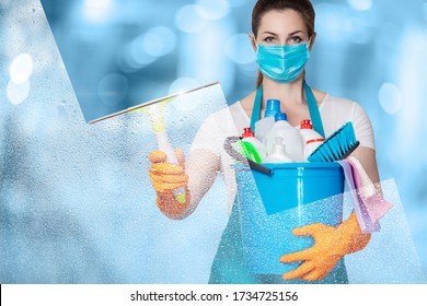 The concept of window cleaning services. A cleaning lady in a mask washes a window on a blurred background.