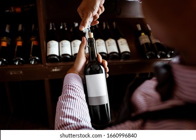 The concept of wine making. A barman demonstrating the cork opening of an expensive wine drink holding in his hands.  A close-up. The corking of expensive wine. - Powered by Shutterstock