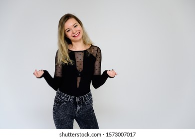 Concept Of A Woman Talking To The Camera. A Photo Of A Pretty Smiling Girl With Long Beautiful Curly Hair In A Black T-shirt On A White Background Is Standing Right In Front Of The Camera.