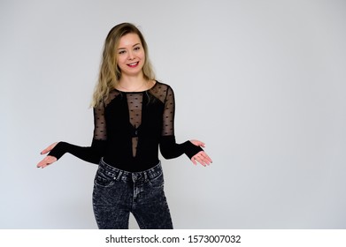 Concept Of A Woman Talking To The Camera. A Photo Of A Pretty Smiling Girl With Long Beautiful Curly Hair In A Black T-shirt On A White Background Is Standing Right In Front Of The Camera.