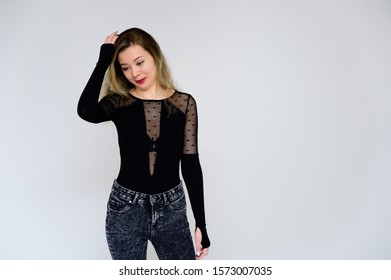 Concept Of A Woman Talking To The Camera. A Photo Of A Pretty Smiling Girl With Long Beautiful Curly Hair In A Black T-shirt On A White Background Is Standing Right In Front Of The Camera.