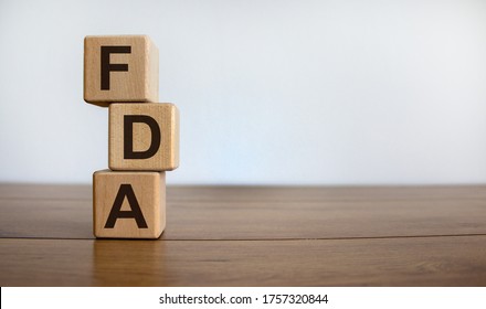 Concept word 'FDA' on cubes on a beautiful wooden table. White background. Business concept. Copy space.