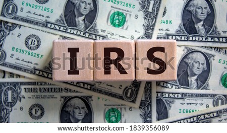 Concept word 'IRS - Internal Revenue Service' on wooden blocks on a beautiful background from dollar bills. Business concept.