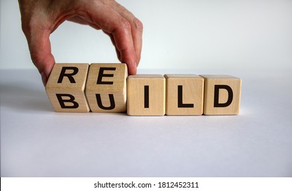 Concept word 'rebuild' on cubes on a beautiful wooden table. Male hand. White background. Business concept. Copy space.