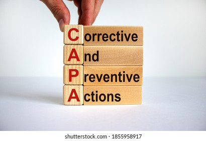 Concept words 'CAPA, corrective and preventive actions' on cubes and blocks on a beautiful white background. Male hand. Business concept. Copy space.