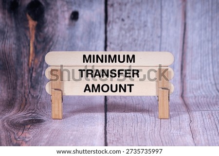 Concept words Minimum Transfer Amount, Triple Wooden Stick Held By Clothespin Light Orange Wooden Texture BG Amount, Business and Minimum Transfer Amount Theme