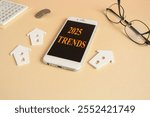 Concept words Tax 2025 on the mobile phone screen. Beautiful beige background. Glasses, miniature houses, coins. Resolution, time, plan, motivation, reboot, countdown and New Year holiday concepts Cop