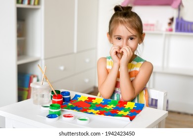 The concept of World Autism Awareness Day. Drawing for World Autism Day. The girl drew bright colorful puzzles. The child folded his hands in the form of a heart. Tolerance - Shutterstock ID 1942423450