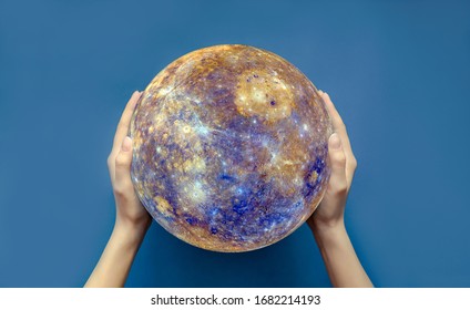 The concept of the world is in your hands. Two female hands hold a globe on a blue isolated background.Elements of this image are provided by NASA. Copy space, top view, selective focus