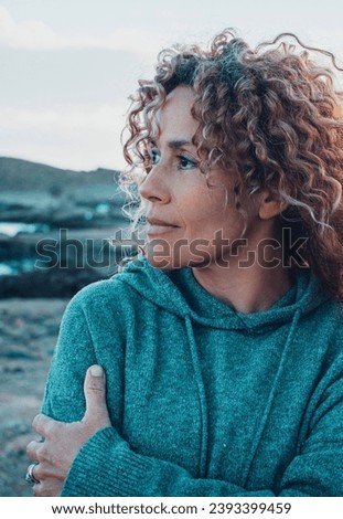 Concept of young woman and emotions. Inner balanced portrait of female enjoying freedom and sensations outdoor. Travel and wanderlust lifestyle people. Beautiul lady with curly long hair smiling
