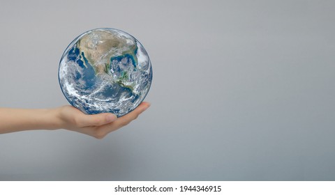 The concept of your world is Planet Earth. A woman's hand holds the planet in the palm of her hand. Close-up, gray isolated background.Elements of this image furnished by NASA.