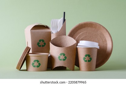 The concept of zero waste and recycling. Use of eco-friendly paper tableware and packaging made from biodegradable materials on a green background. - Shutterstock ID 2205879965