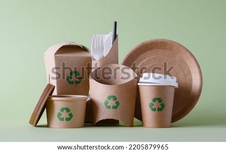 The concept of zero waste and recycling. Use of eco-friendly paper tableware and packaging made from biodegradable materials on a green background.