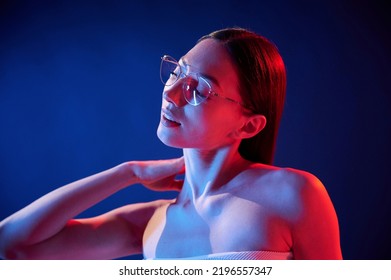 Conception Of Bad Sight, In Glasses. Portrait Of Young Woman That Is Indoors In Neon Lighting.