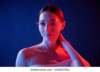 Conception Of Bad Sight, In Glasses. Portrait Of Young Woman That Is Indoors In Neon Lighting.