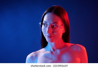 Conception Of Bad Sight, In Glasses. Portrait Of Young Woman That Is Indoors In Neon Lighting.